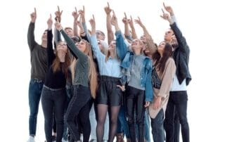 Fotografia de um grande grupo de pessoas reunidas, todas olhando e apontando com o dedo indicador para cima na mesma direção, servindo de metáfora visual para o comportamento de manada e o FOMO (medo de ficar de fora) no day trade.
